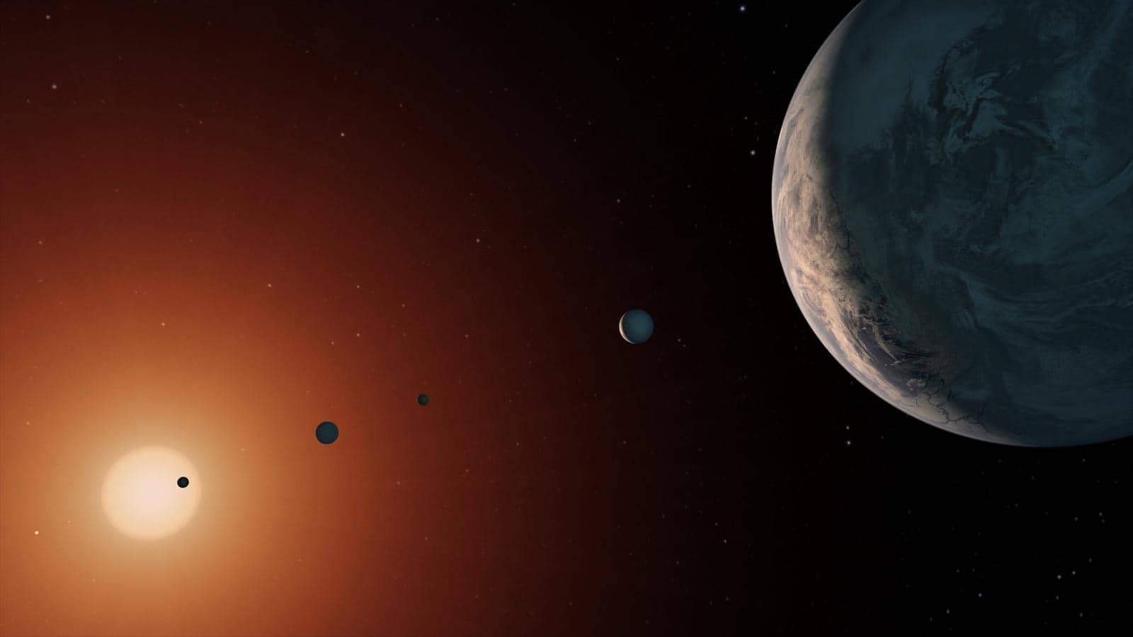 Concetto artistico del sistema TRAPPIST-1 con la nana rossa e i pianeti rocciosi
