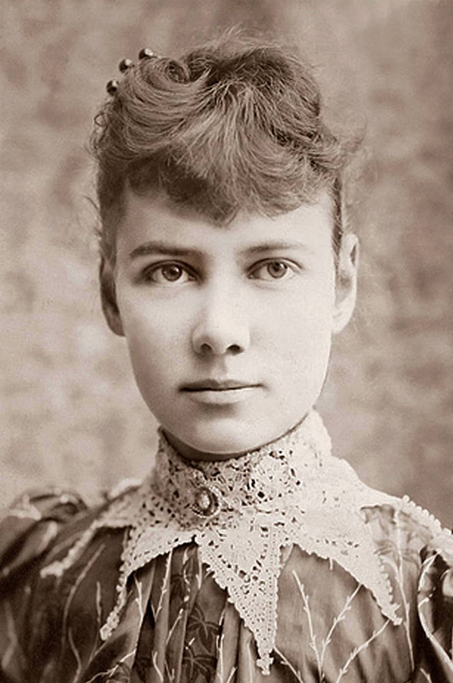 Nellie Bly in abito da viaggio con cappotto e borsa