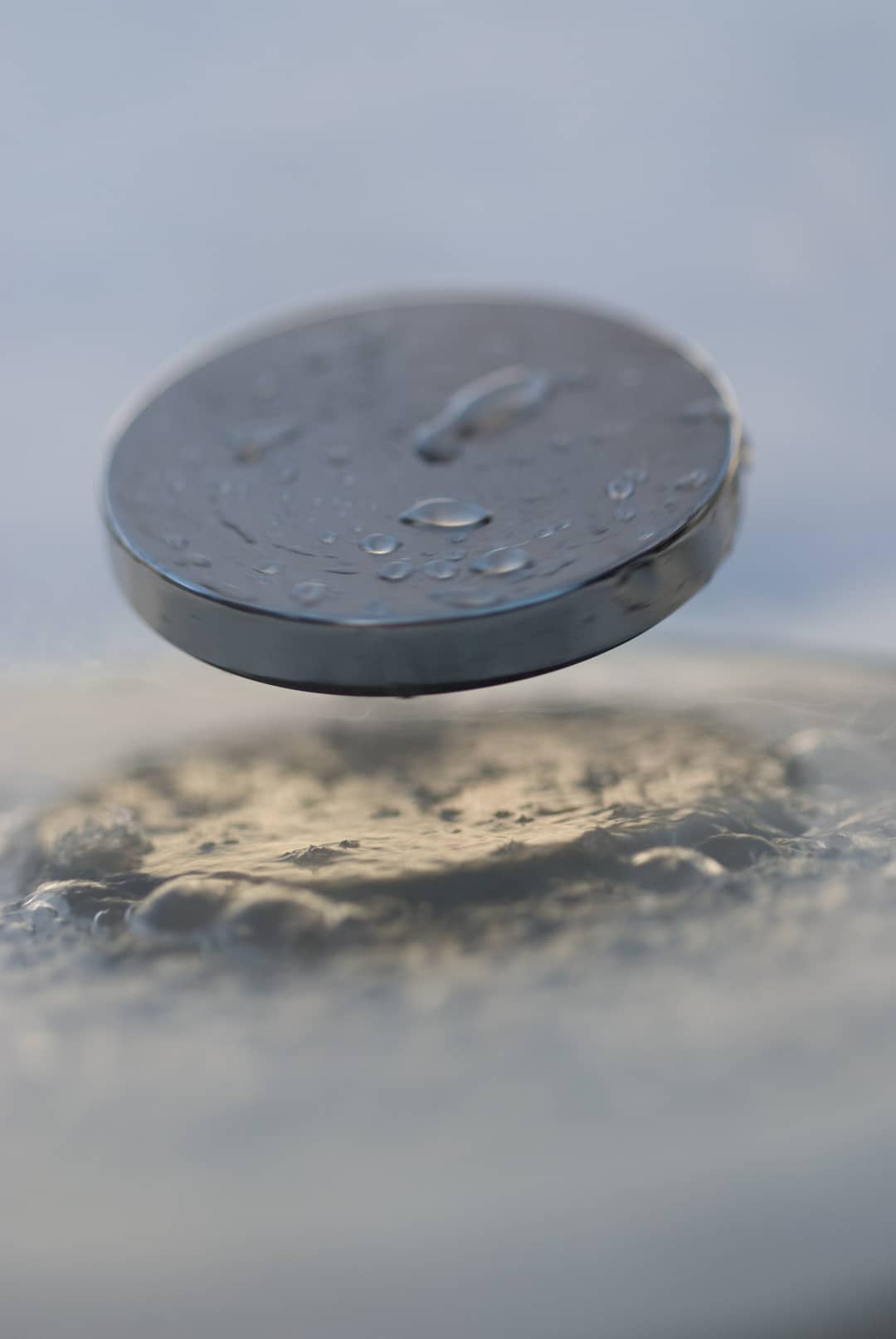 Piccolo magnete che levita sopra un superconduttore raffreddato, con vapore freddo intorno