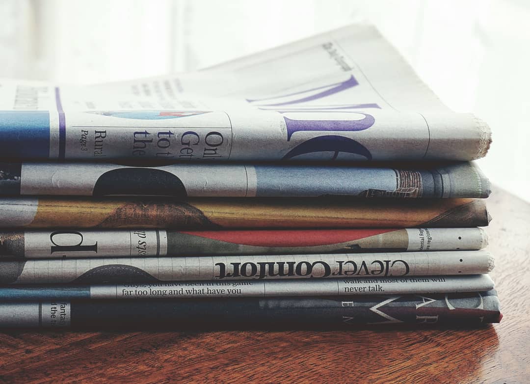 Pila di giornali con titoli di cronaca che evocano cattive notizie