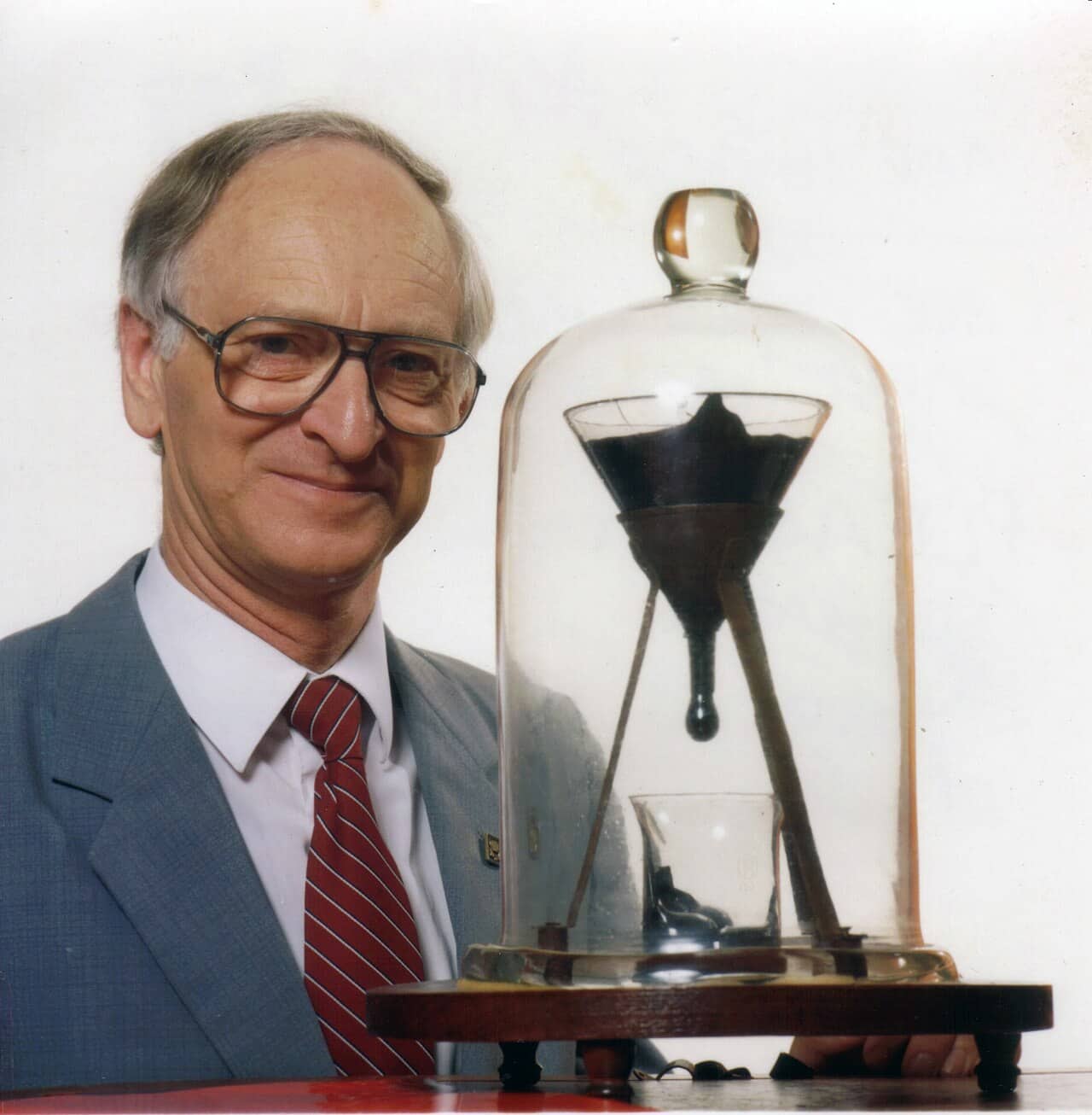 John Mainstone accanto all'esperimento della goccia di pece all'Università del Queensland
