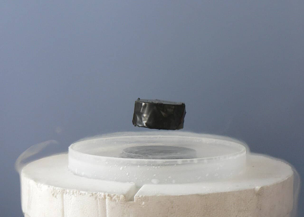 Magnete che levita sopra un superconduttore raffreddato con azoto liquido, avvolto dal vapore freddo
